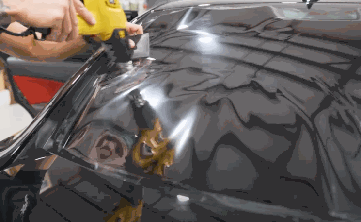 A heat gun is used to mold window tint to the curved shape of a rear windshield during installation.