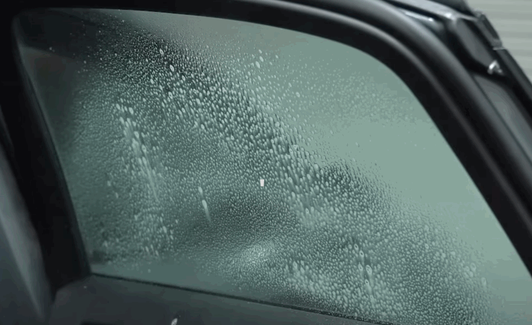 A car window is prepped with a fine mist of water to prepare the surface for window tint film application